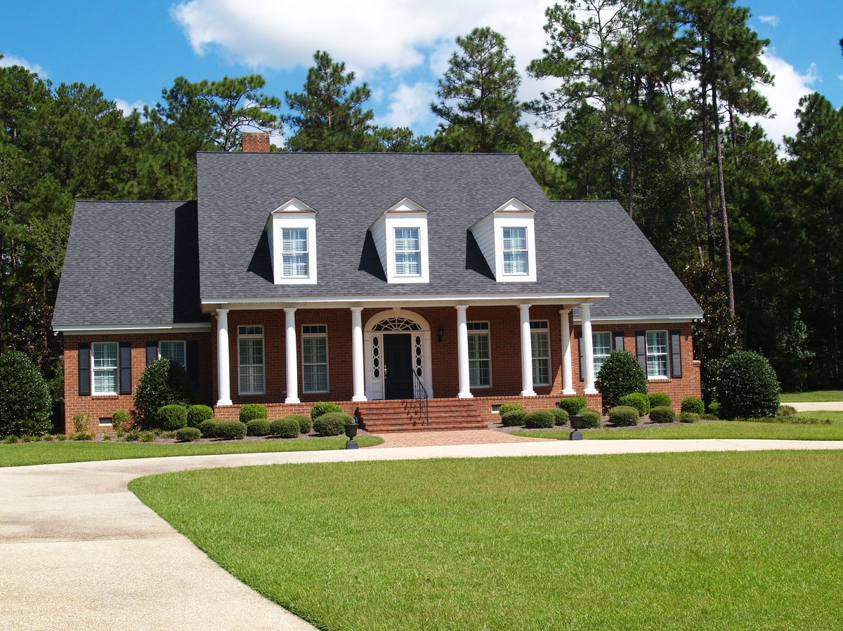 Two story brick residential home with large front porch and side entrance garage
